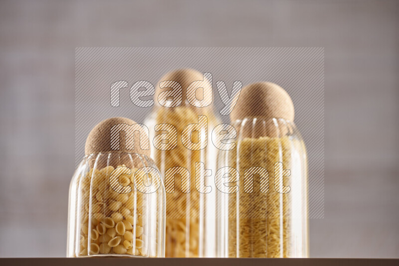 Raw pasta in glass jars on beige background