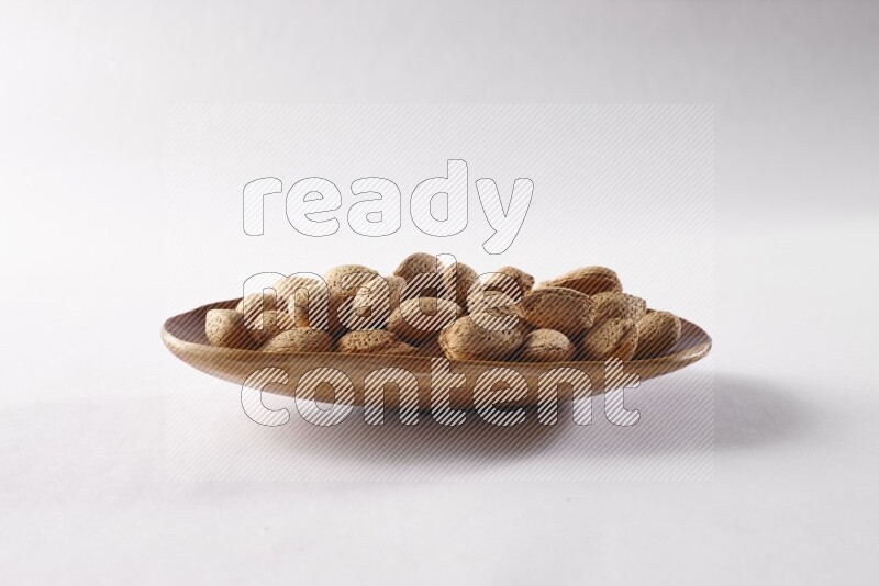 Almonds in a wooden plate on white background