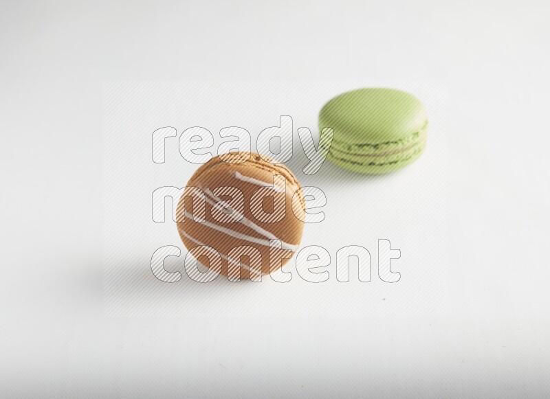 45º Shot of of two assorted Brown Irish Cream, and Green Pistachio macarons on white background