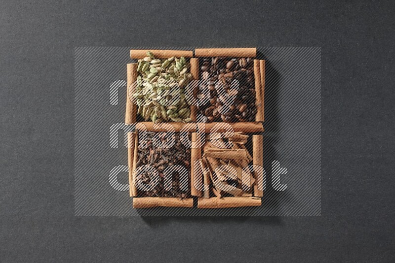 4 squares of cinnamon sticks full of coffee beans, cinnamon, cloves and cardamom on black flooring