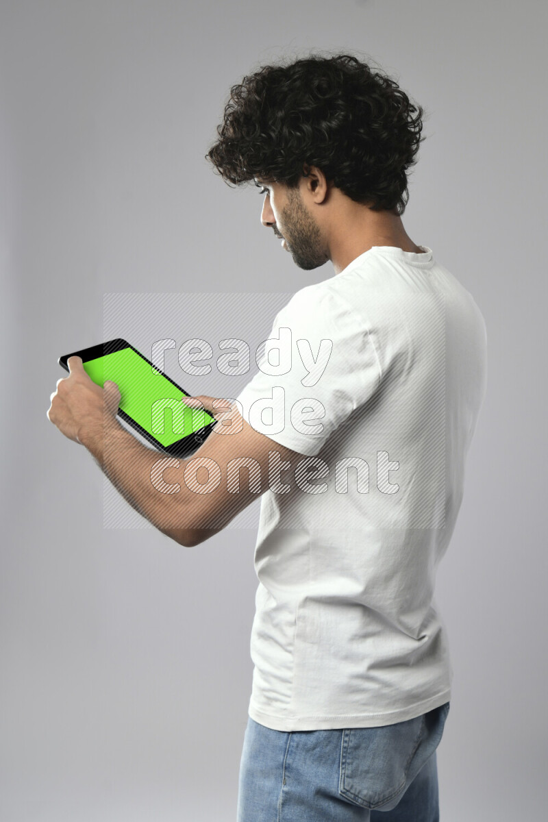 A man wearing casual standing and browsing on a tablet on white background