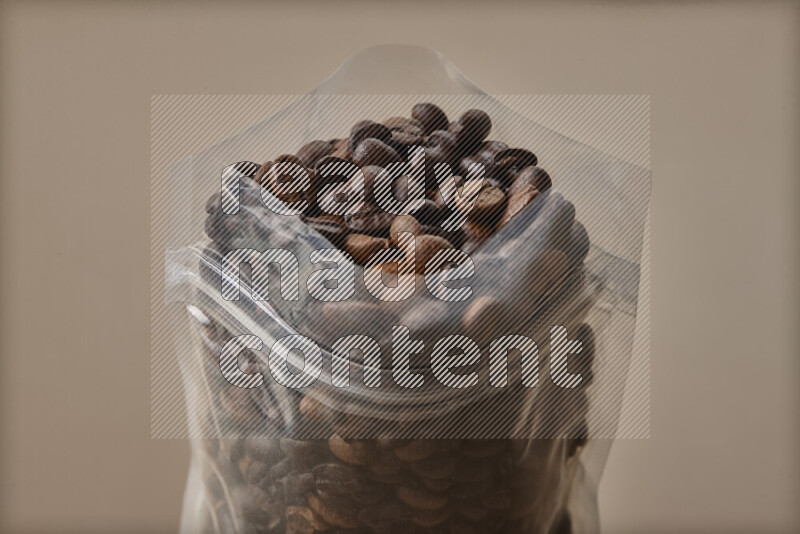 Spilled roasted coffee beans from its pack on beige background