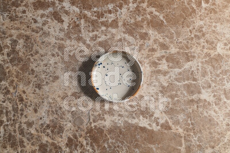 A multicolored pottery bowl on beige marble background