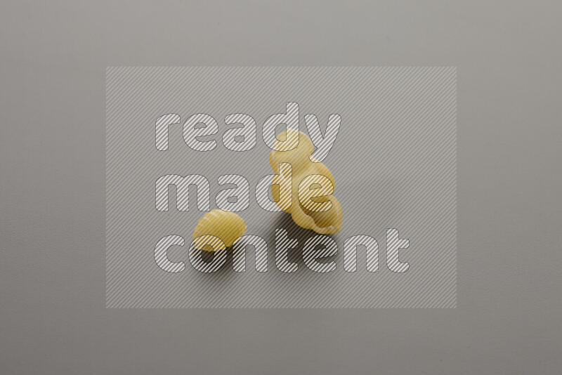 Shells pasta with other types of pasta on grey background