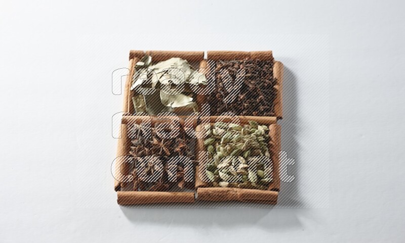 4 squares of cinnamon sticks full of cardamom, star anise, cloves and bay laurel leaves on white flooring