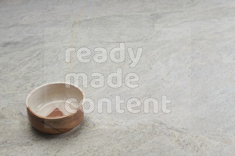 A multicolored pottery bowl on grey marble background