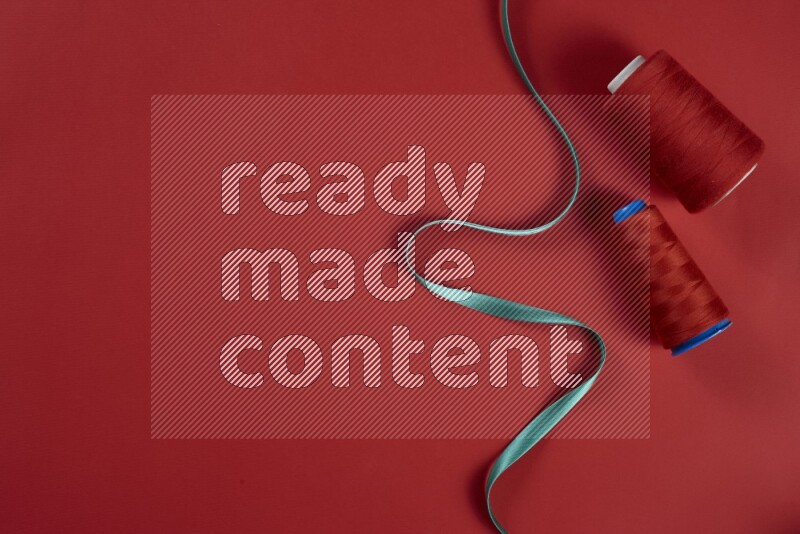 A green and red collection of sewing and tailoring tools arranged on a red background