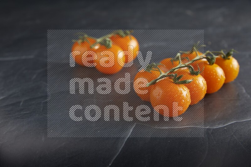 Orange cherry tomato vein on a textured black slate background 45 degree