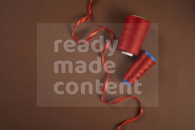 مجموعة من أدوات الخياطة والتفصيل حمراء اللون على خلفية بنية