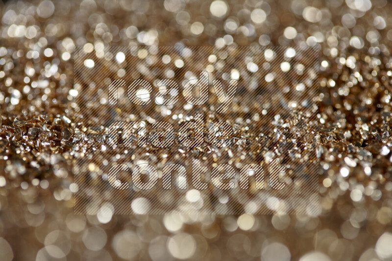 Gold shimmering fragments of glass scattered on a black background