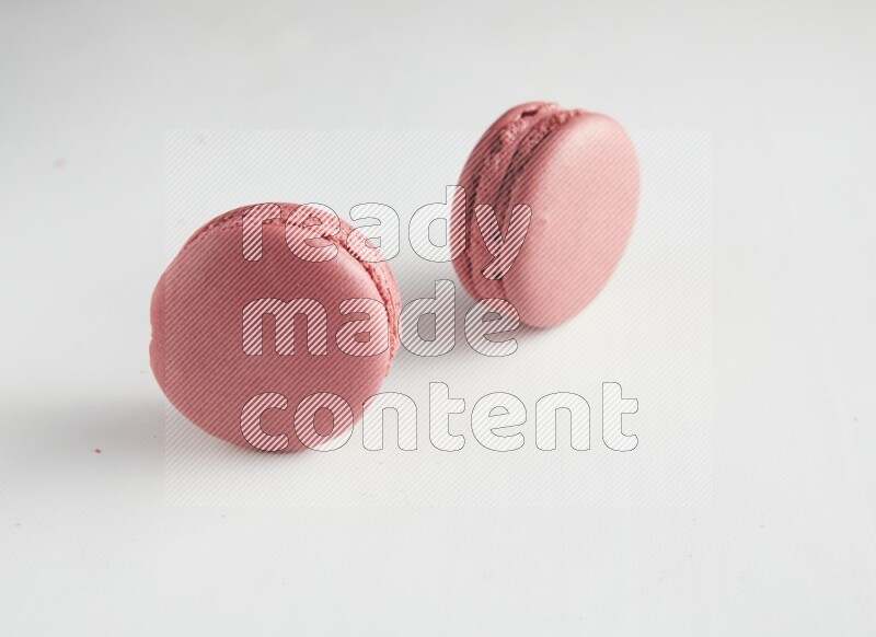 45º Shot of two Pink Raspberry macarons on white background