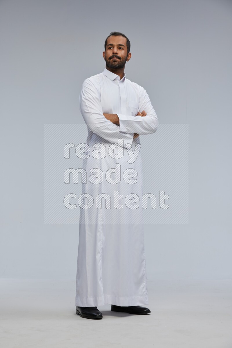Saudi man wearing Thob standing with crossed arms on Gray background