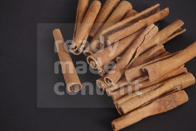 Cinnamon sticks stacked on black flooring