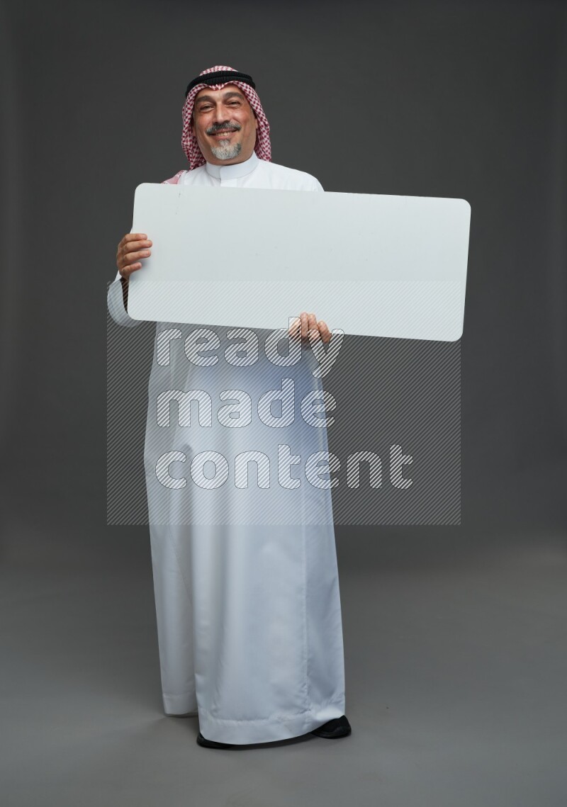 Saudi man with shomag Standing holding social media sing on gray background