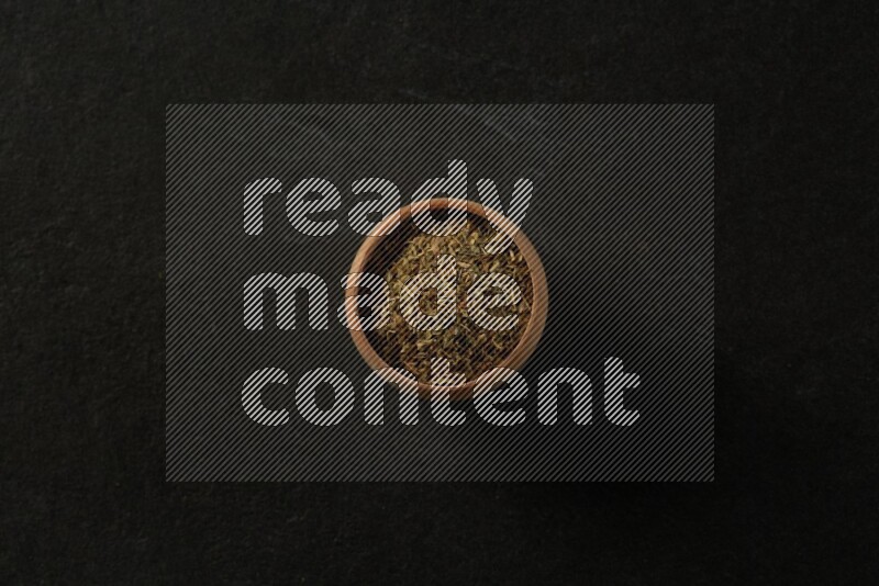wooden round sauce bowl filled with herbs on grey textured countertop