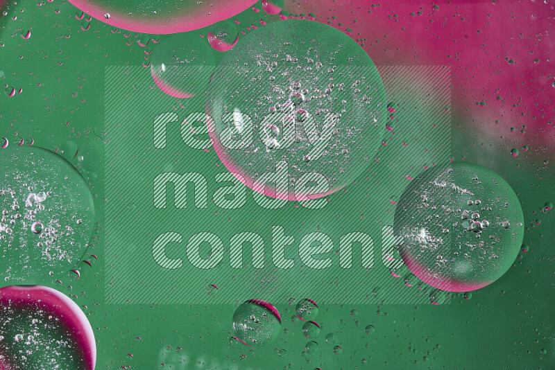 Close-ups of abstract oil bubbles on water surface in shades of green and pink