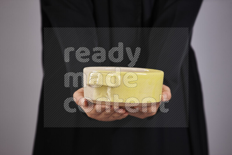 A woman in black abaya holding different pottery essentials in different positions