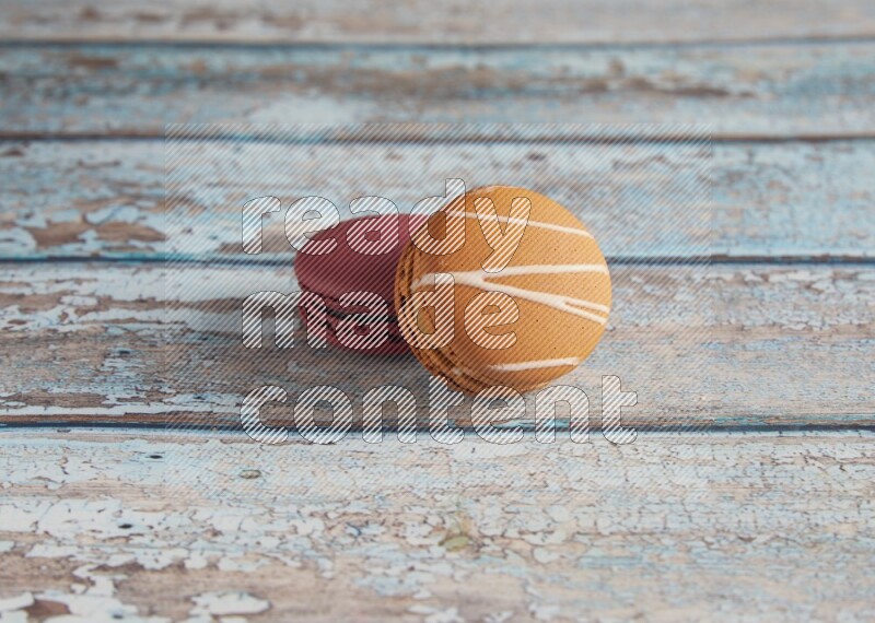 45º Shot of of two assorted Brown Irish Cream, and Red Cherry macarons  on light blue background