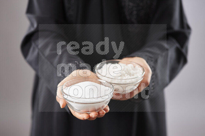 Woman in abaya holding different kinds of spices in different positions