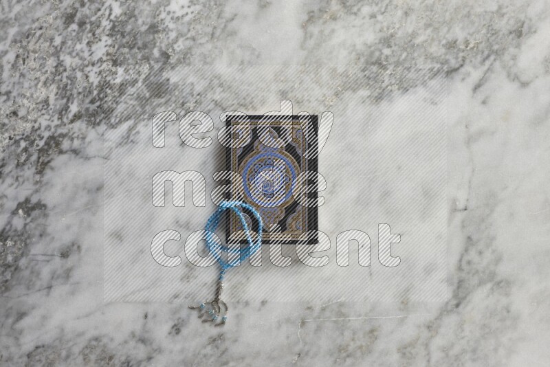 Quran with a prayer beads on grey marble background