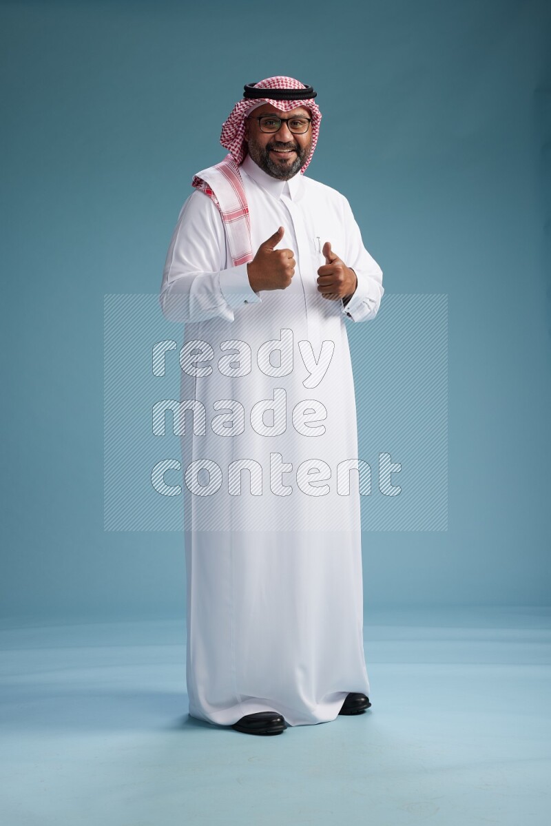 Saudi Man with shimag Standing Interacting with the camera on blue background