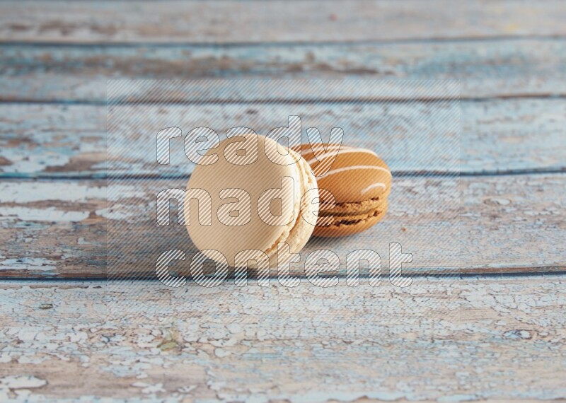 45º Shot of of two assorted Brown Irish Cream, and White Caramel fleur de sel macarons on light blue background