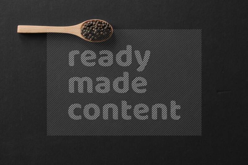 الفلفل الأبيض والقرنفل والهيل والملح والفلفل الأسود وريحان مجفف في معالق خشبية علي خلفية سوداء