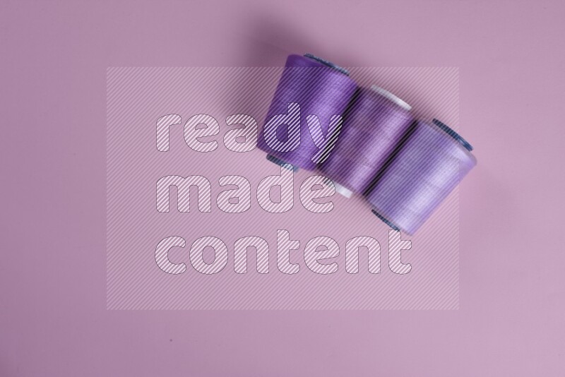 A purple and pink collection of sewing and tailoring tools arranged on a pink background