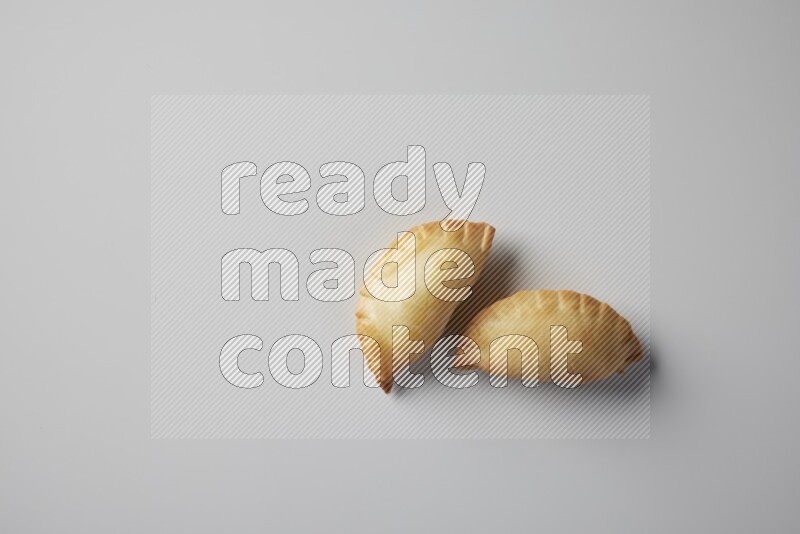 Two fried sambosa from a top angle on a white background