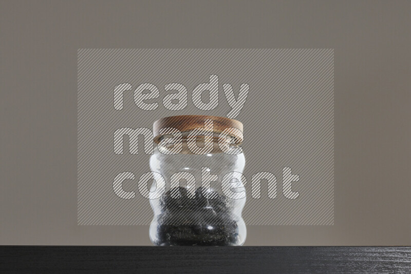 Dried plums in a glass jar on black background