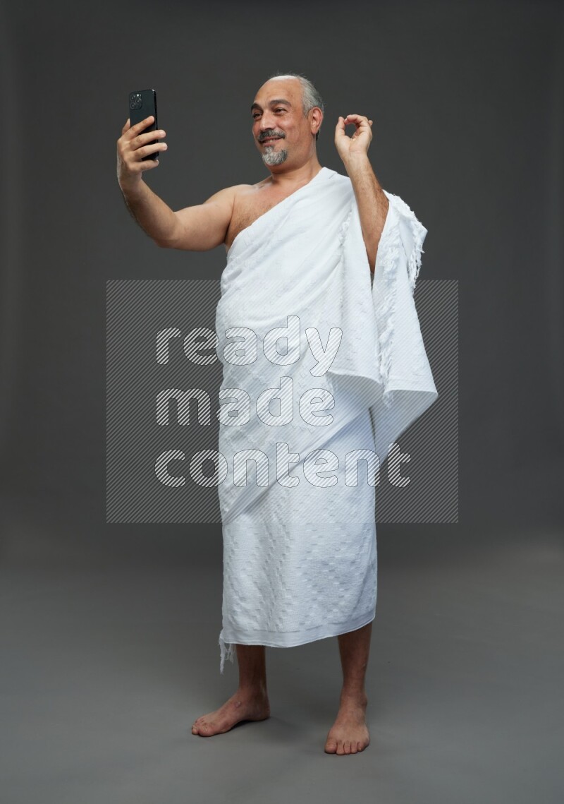 A man wearing Ehram Standing taking selfie on gray background