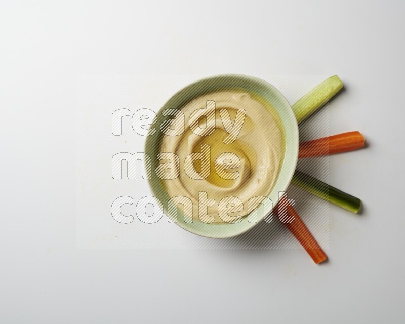 Hummus in a green plate garnished with olive oil on a white background
