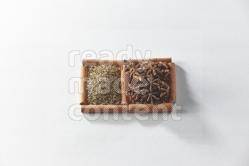 مربعان من أعواد القرفة ممتلئان باليانسون النجمي والكمون علي خلفية بيضاء