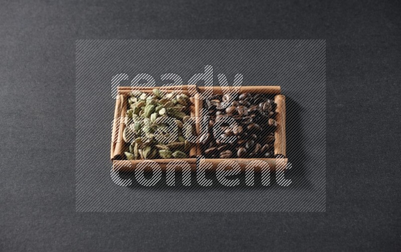 مربعان من أعواد القرفة ممتلئان بحبوب القهوة وحبوب الهيل علي خلفية سوداء