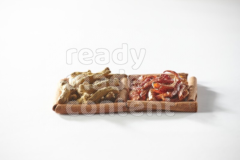 2 squares of cinnamon sticks full of dried red chilis and turmeric fingers on white flooring