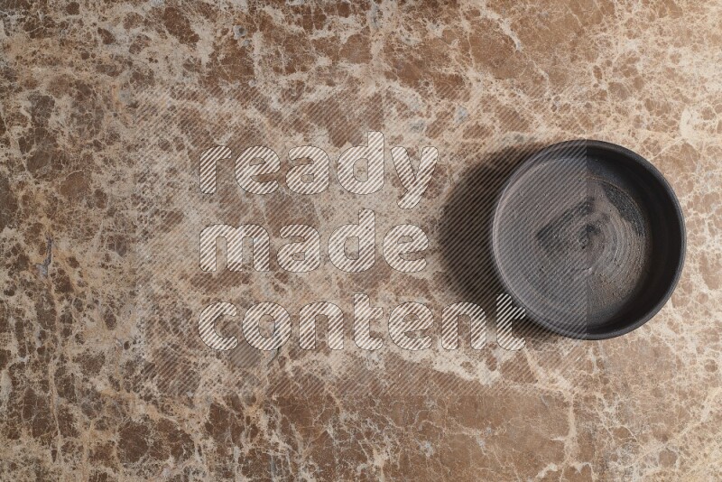 A black pottery oven plate on beige marble background