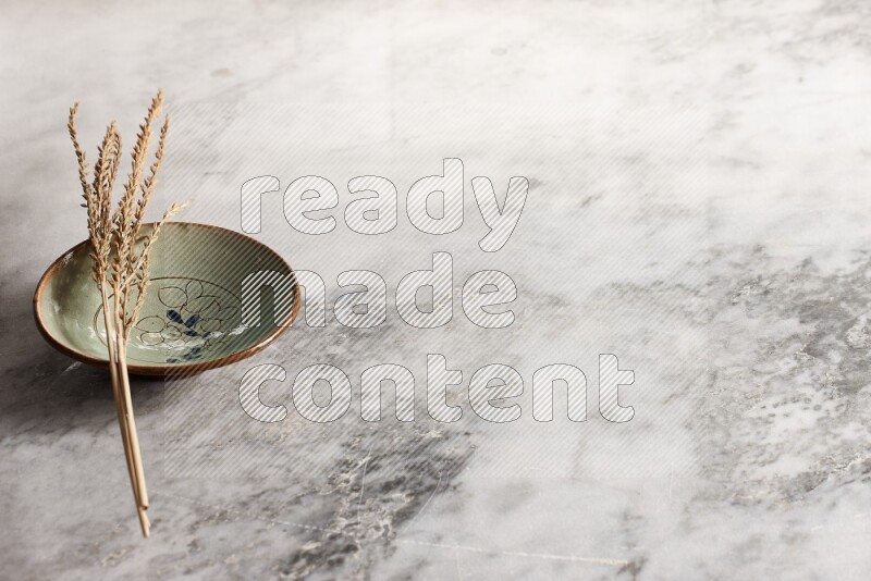 Wheat stalks on decorative pottery plate on grey marble background