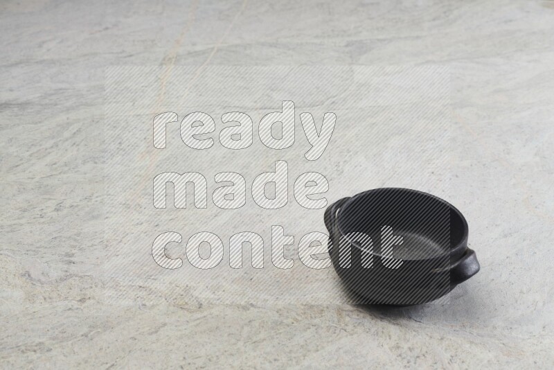 A black pottery bowl on grey marble background