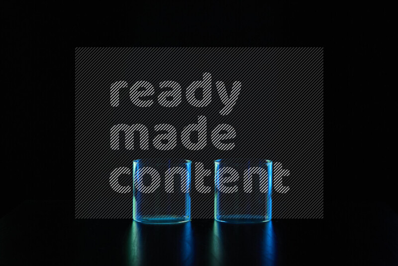 أواني زجاجية مع حواف مضيئة باللونين الأزرق والأخضر على خلفية سوداء