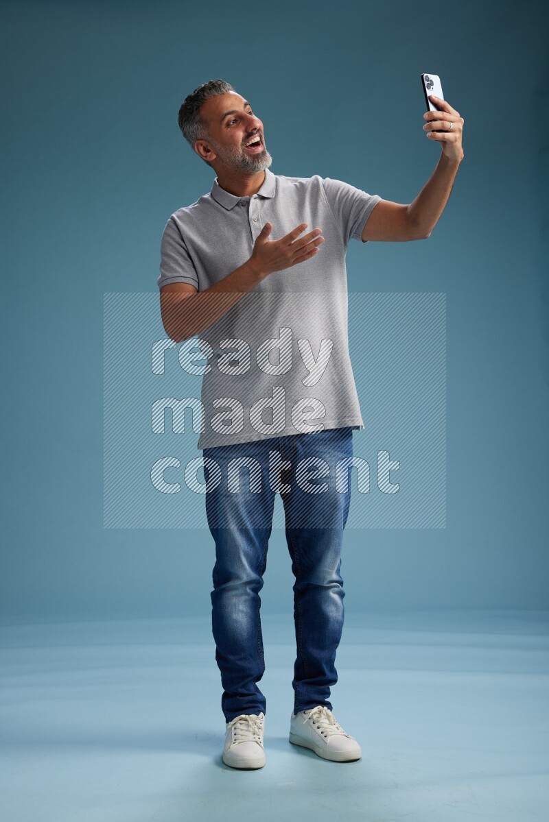 Man Standing taking selfie on blue background