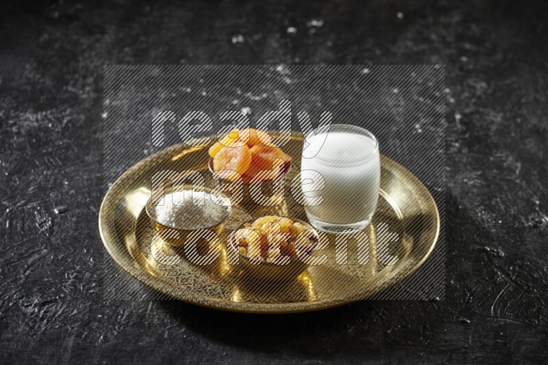 Dried fruits in metal bowls with sobya on a tray in dark setup