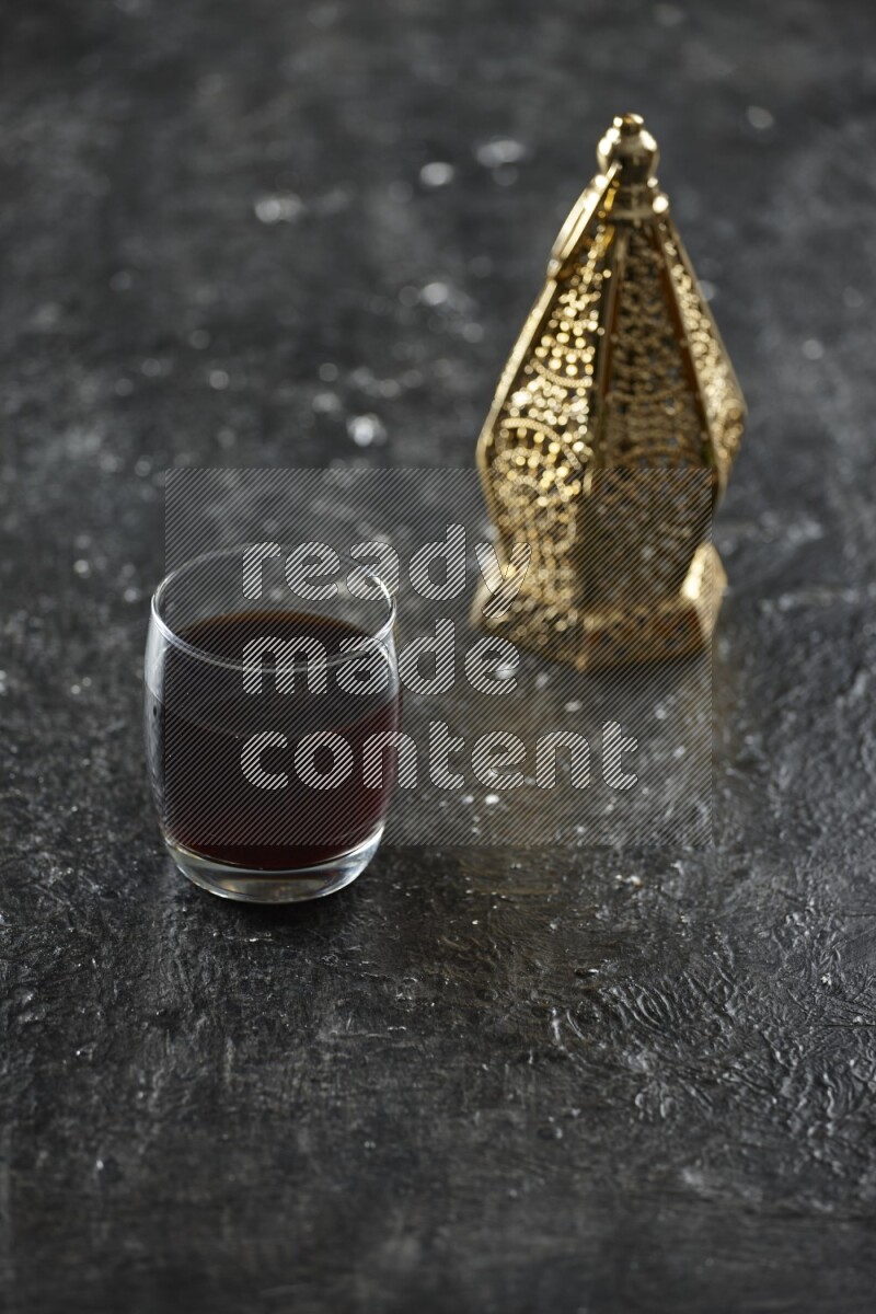 A golden lantern with different drinks, dates, nuts, prayer beads and quran on textured black background