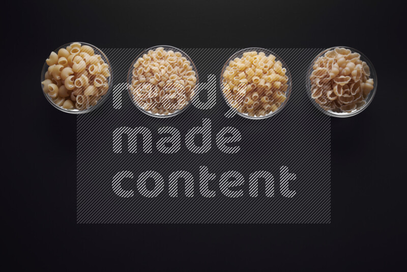 أنواع مختلفة من المعكرونة في وعاء زجاجي علي خلفية سوداء