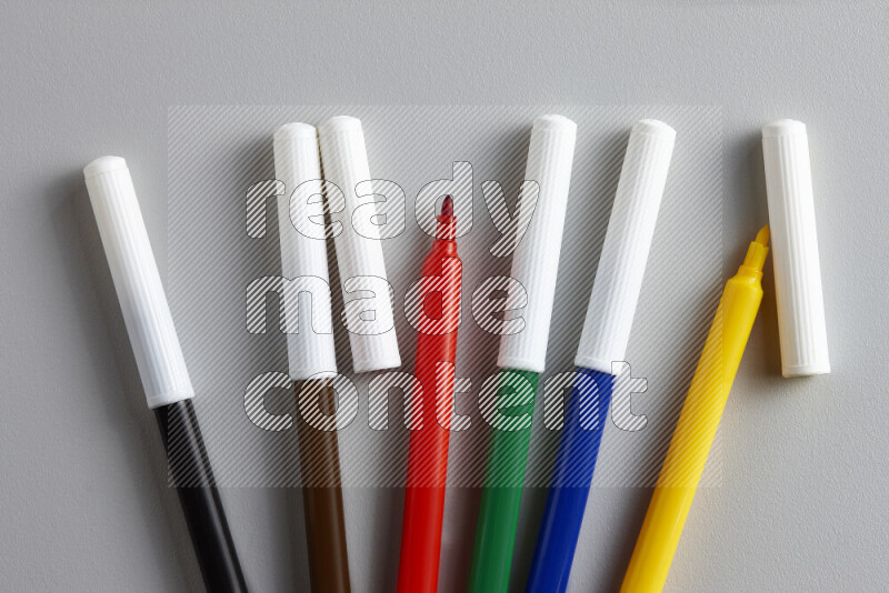 An arrangement of coloring pens in different colors on grey background