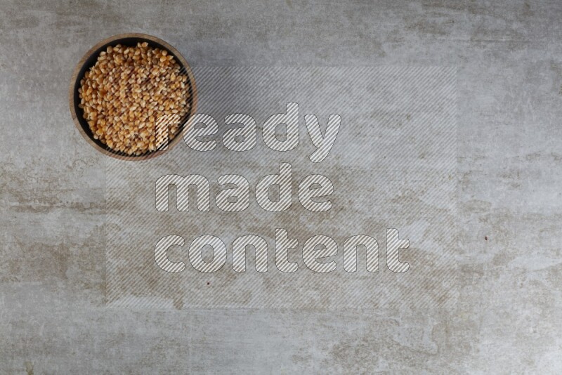 corn kernel in a wooden bowl on a grey textured countertop