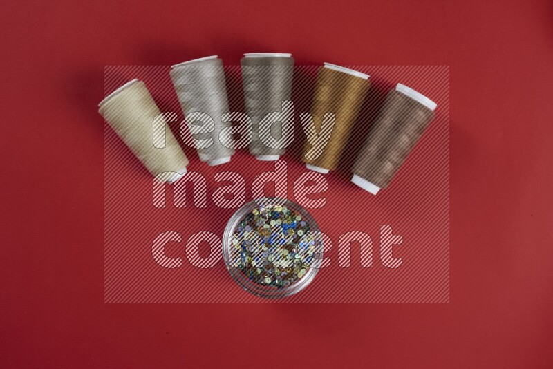 A brown and red collection of sewing and tailoring tools arranged on a red background