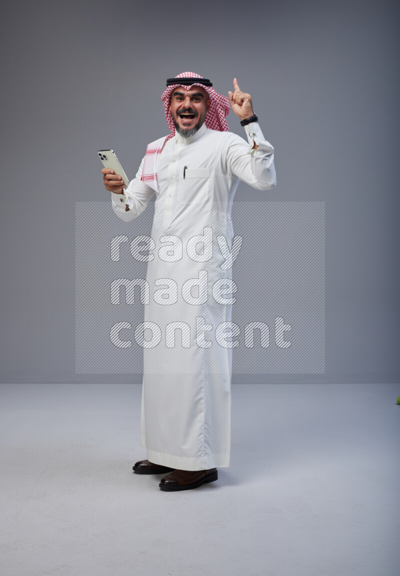 Saudi woman wearing Abaya with engineer vest and helmet standing holding ATM card on pink background